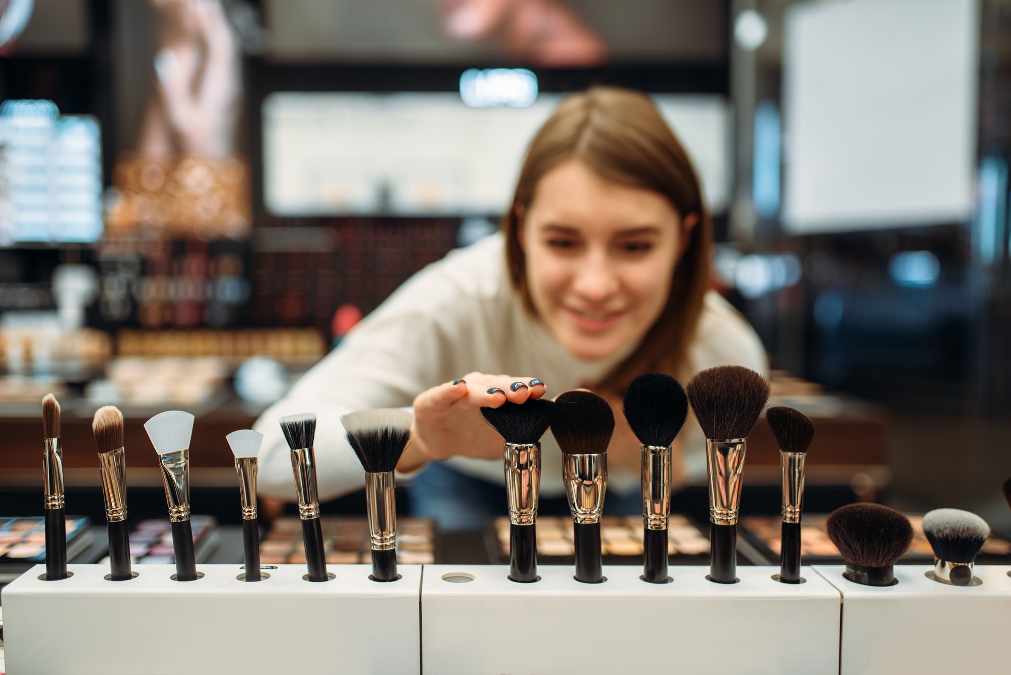 Female customer choosing brushes in makeup shop