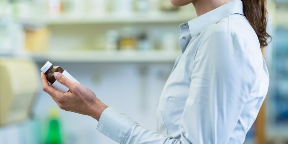 Pharmacist checking a bottle of drug in pharmacy